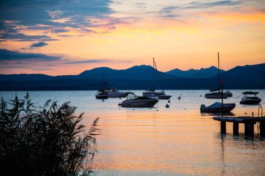 Bardolino 'da gün batımı Garda Gölü' nde, arkasında dağlar var.