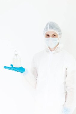 Koruyucu kıyafetli bir adam el dezenfeksiyonu için antibakteriyel antiseptik jel tutuyor. Grip salgını ve koronavirüs salgını sırasında sağlık hizmetlerinin önlenmesi