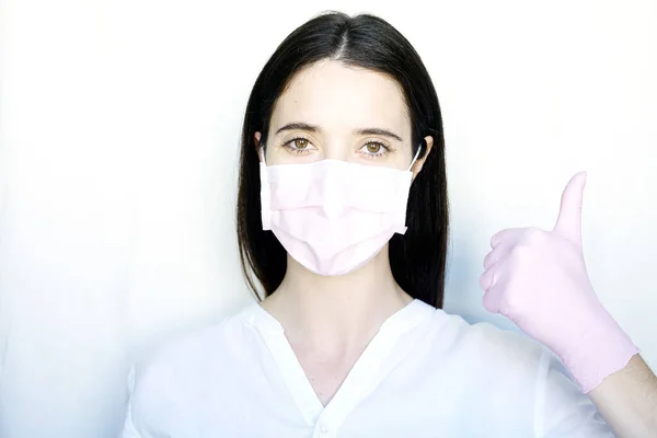 一个戴着粉色防护面具和粉色手套的女人也有类似的标志 这个女孩穿着白衣站在浅色的背景上 抑制头孢病毒的概念 — 图库照片