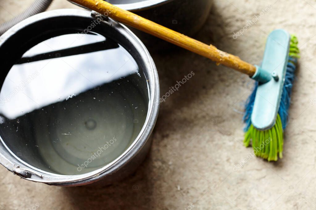 Floor brush and bucket of water. Concept of cleaning in a private yard