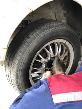 Dışarıda lastik değiştiren elektrikli tornavidalı oto tamircisi. Araba servisi. Lastik kurulumu konsepti. Kış ve yaz lastiklerinin değiştirilmesi. Eller tekerlekleri değiştirir..