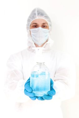 Koruyucu kıyafetli bir adam el dezenfeksiyonu için antibakteriyel antiseptik jel tutuyor. Grip salgını ve koronavirüs salgını sırasında sağlık hizmetlerinin önlenmesi