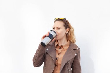 Kızın elinde demir bir termo bardak var. Beyaz arka planda. Çevre dostu kavram