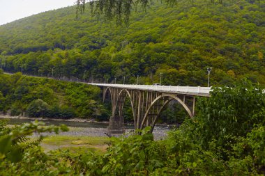 Yol boyunca uzanan dağ nehri, bulutlar, sis, köprü ve viyadük ile kaplı güzel manzaralı bir çevre yolu boyunca uzanan dağ nehri.,