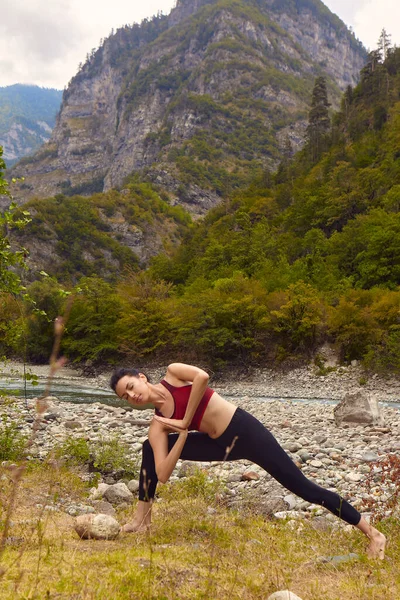 自然の中でヨガのクラス 女性は山の中でヨガをします 山の川の近くに流れます 一人でスポーツをするというコンセプト 社会的排除 — ストック写真