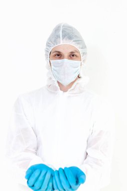 Koruyucu takım elbiseli ve yüz maskeli bir adam. Beyaz arka planda izole edilmiş şişe ya da kavanoz gibi bir şey tutuyor.