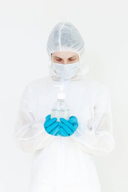 Koruyucu kıyafetli bir adam el dezenfeksiyonu için antibakteriyel antiseptik jel tutuyor. Grip salgını ve koronavirüs salgını sırasında sağlık hizmetlerinin önlenmesi