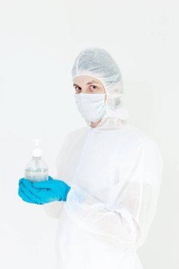 Koruyucu kıyafetli bir adam el dezenfeksiyonu için antibakteriyel antiseptik jel tutuyor. Grip salgını ve koronavirüs salgını sırasında sağlık hizmetlerinin önlenmesi