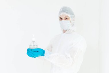 Koruyucu kıyafetli bir adam el dezenfeksiyonu için antibakteriyel antiseptik jel tutuyor. Grip salgını ve koronavirüs salgını sırasında sağlık hizmetlerinin önlenmesi