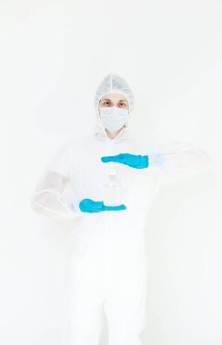 Koruyucu kıyafetli bir adam el dezenfeksiyonu için antibakteriyel antiseptik jel tutuyor. Grip salgını ve koronavirüs salgını sırasında sağlık hizmetlerinin önlenmesi