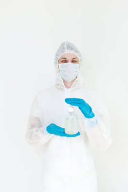 Koruyucu kıyafetli bir adam el dezenfeksiyonu için antibakteriyel antiseptik jel tutuyor. Grip salgını ve koronavirüs salgını sırasında sağlık hizmetlerinin önlenmesi