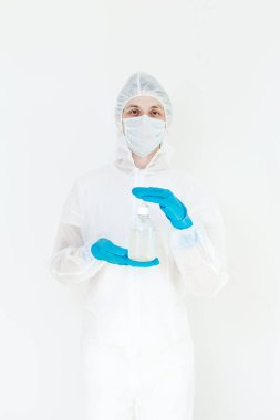 Koruyucu kıyafetli bir adam el dezenfeksiyonu için antibakteriyel antiseptik jel tutuyor. Grip salgını ve koronavirüs salgını sırasında sağlık hizmetlerinin önlenmesi