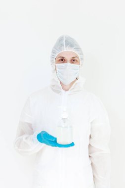 Koruyucu kıyafetli bir adam el dezenfeksiyonu için antibakteriyel antiseptik jel tutuyor. Grip salgını ve koronavirüs salgını sırasında sağlık hizmetlerinin önlenmesi