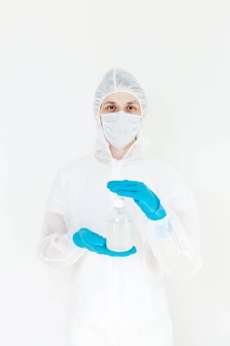 Koruyucu kıyafetli bir adam el dezenfeksiyonu için antibakteriyel antiseptik jel tutuyor. Grip salgını ve koronavirüs salgını sırasında sağlık hizmetlerinin önlenmesi
