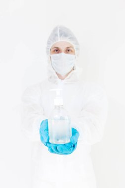 Koruyucu kıyafetli bir adam el dezenfeksiyonu için antibakteriyel antiseptik jel tutuyor. Grip salgını ve koronavirüs salgını sırasında sağlık hizmetlerinin önlenmesi