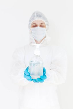 Koruyucu kıyafetli bir adam el dezenfeksiyonu için antibakteriyel antiseptik jel tutuyor. Grip salgını ve koronavirüs salgını sırasında sağlık hizmetlerinin önlenmesi
