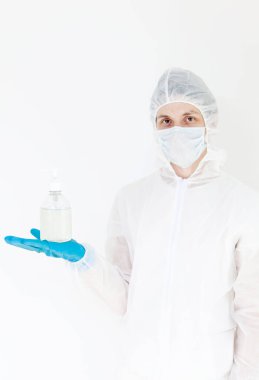 Koruyucu kıyafetli bir adam el dezenfeksiyonu için antibakteriyel antiseptik jel tutuyor. Grip salgını ve koronavirüs salgını sırasında sağlık hizmetlerinin önlenmesi