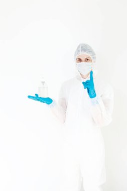 Koruyucu kıyafetli bir adam el dezenfeksiyonu için antibakteriyel antiseptik jel tutuyor. Grip salgını ve koronavirüs salgını sırasında sağlık hizmetlerinin önlenmesi