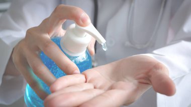 Hastane üniformalı bir kadın doktorun yakın çekimi, sağlıklı yaşam, hijyenik ve hijyenik yaşam için antibakteriyel ve koronavirüs veya COVID-19 hastalıklarından korunmak amacıyla el temizleme jeli ile avuç içi temizleme jeli ile ovuşturuluyor
