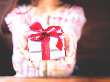 Kırmızı kurdele ya da hediye paketi kadınların elinde. Noel ya da doğum günü hediyesi ve şükran günü, daha fazla kavram verir. Sevgililer Günü 'nde sevgi gösteren insanlar.