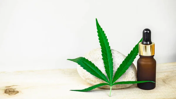 Cannabis leaves and oil extract in bottle to soothe pains, in white background