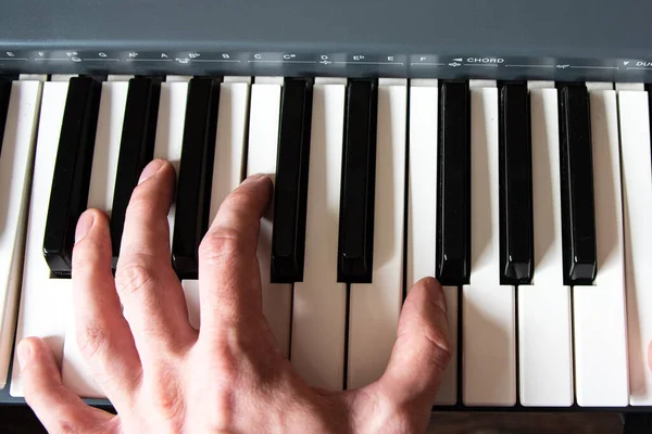 Male playing the piano keyboard. Hand close up.