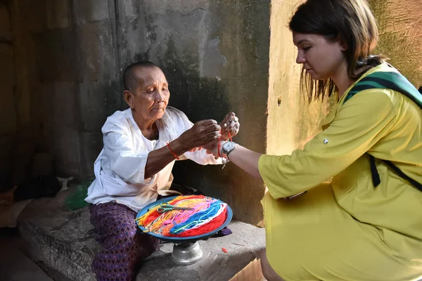 Siem Reap, Kamboçya - 15 01 2019 - Yaşlı Kadın Bilek Bandında Kırmızı İplik Koyuyor.