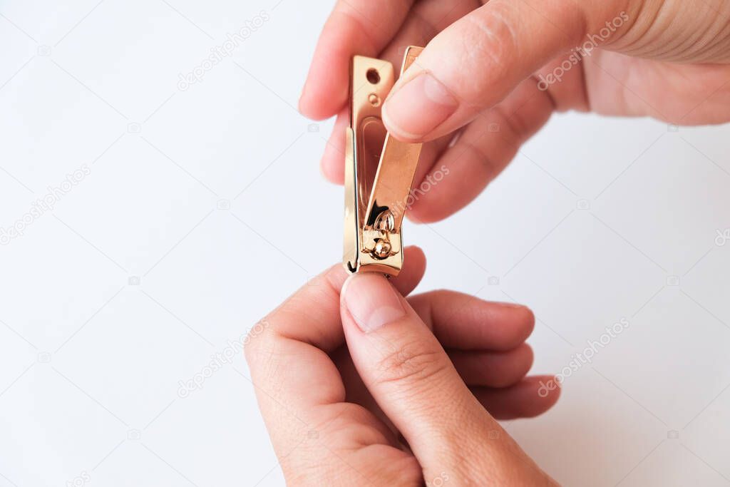 Woman hands using a nail clippers to cut her fingernails on a white background. View from above. Manicure at home.