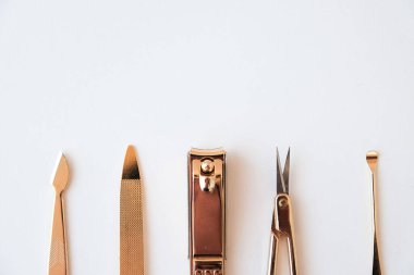 Beyaz bir arkaplanda manikür seti. Altın rengi araçlar.