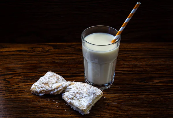 fresh bakery with a glass of milk on a dark wooden background close up.