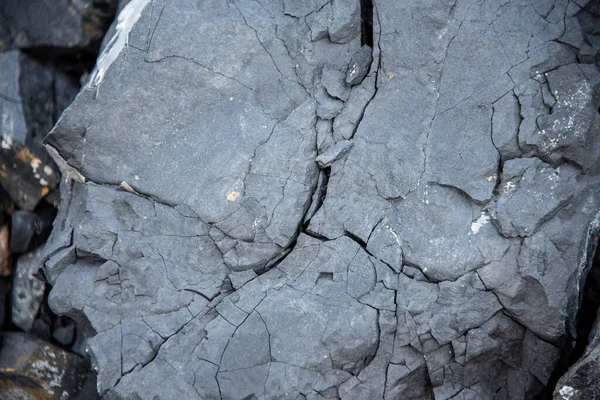 Black texture. Rough structure. Stone black wall. Rock texture. Stone background. Black background. Stone texture. Rock surface with cracks.