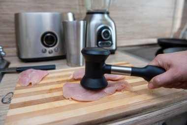 Kadın elleri tavuk filetosunu çekiçle döver..