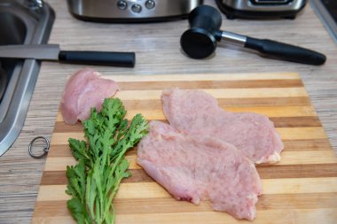 Mutfak masasındaki tahtanın üzerinde siyah kağıt ve roka ile tavuk bifteği..