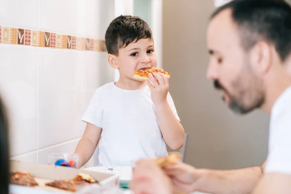Bir aile kendi mutfağında pizza yer.