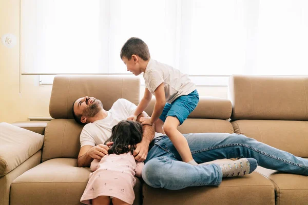 Um pai brinca com seus filhos no sofá — Fotografia de Stock