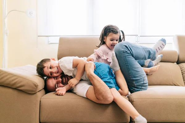 En far leker med sina barn på soffan — Stockfoto