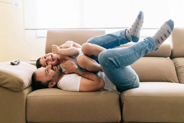 A father plays with his son on the couch — Stock Photo, Image