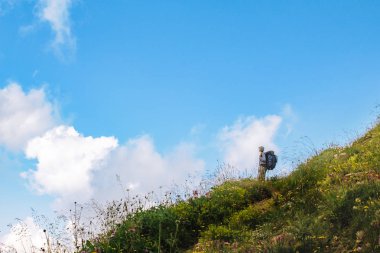 Sırt çantası olan bir kadın gökyüzüne bakıyor. Kopya alanı ile Dağ yaz manzara
