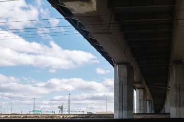 Gün boyunca kentin sanayi bölgesinin beton yapı viyadüğü mavi gökyüzü ve bulutlara karşı