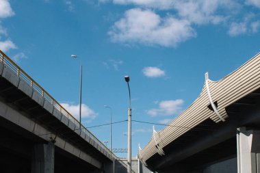Gün boyunca kentin sanayi bölgesinin beton yapı viyadüğü mavi gökyüzü ve bulutlara karşı