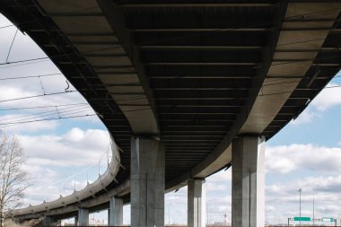 Gün boyunca kentin sanayi bölgesinin beton yapı viyadüğü mavi gökyüzü ve bulutlara karşı