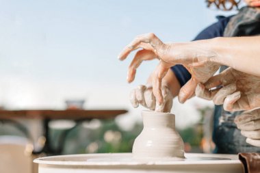 Sanat terapisi. Kadınların elleri çömlekçi tekerleğinde kilden bir çömlek yapar. Çömlekçilik Atölyesi