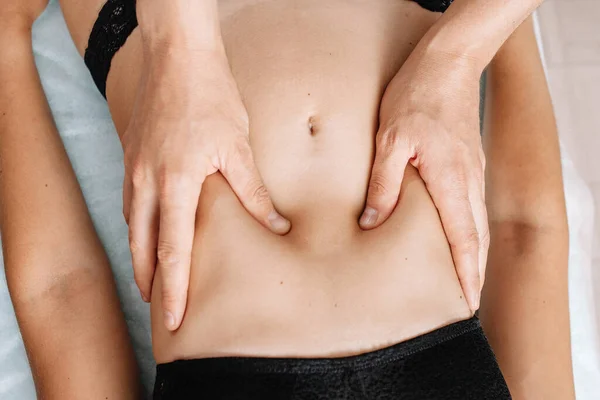 Kadın karnına masaj yapan ellerin üst görüntüsü. Terapist, osteopat, mideye baskı uyguluyor. Kadın spa salonunda masaj yaptırıyor. Doktorda..