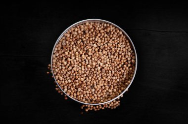 Kasede renkli kişniş baharatları, arka planda koyu bir manzara, lezzetli yemekler için baharat.