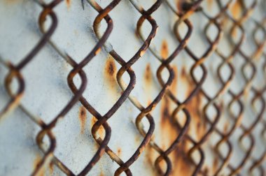 Paslı bir çelik duvarın arkasında paslı bir rabitz. Yan görüş. Kapat..