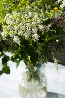 Güneşli bir yaz gününde şeffaf bir vazoda narin çayır çiçekleri..