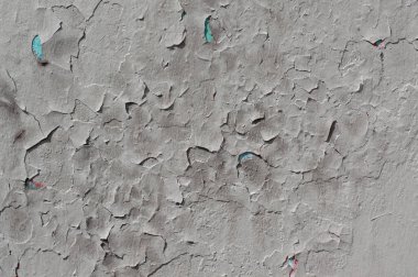 Eski, çatlak, açık gri boya güneşli bir günde duvarda.