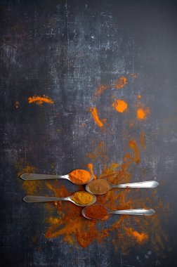 Koyu arkaplana yayılmış çeşitli baharatlı kaşıklar.