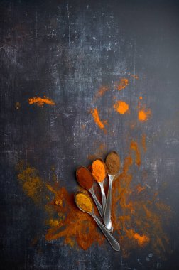 Koyu arkaplana yayılmış çeşitli baharatlı kaşıklar.