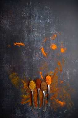 Koyu arkaplana yayılmış çeşitli baharatlı kaşıklar.